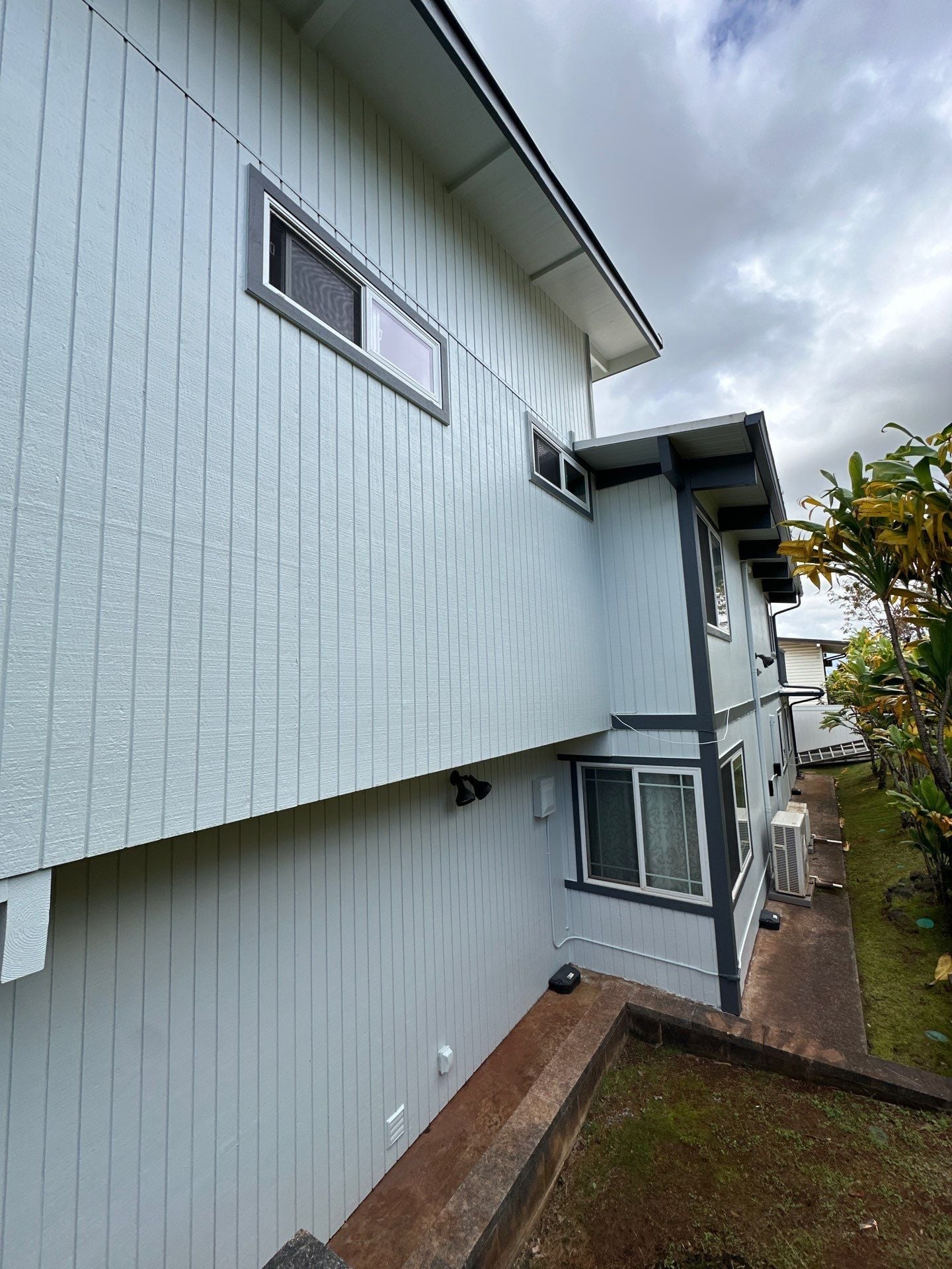 Side elevation of a home repainted in pale blue-green in Maui, Hawaii