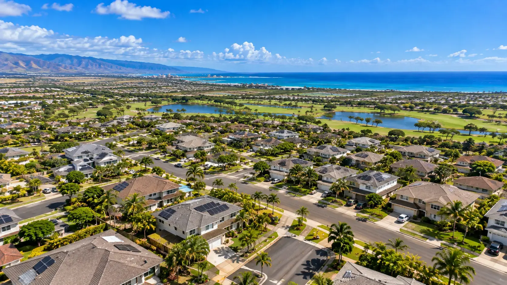 Aerial drone view of residential neighborhoods in Ewa Beach, Oahu, Hawaii, with the Pacific Ocean and mountains in the background