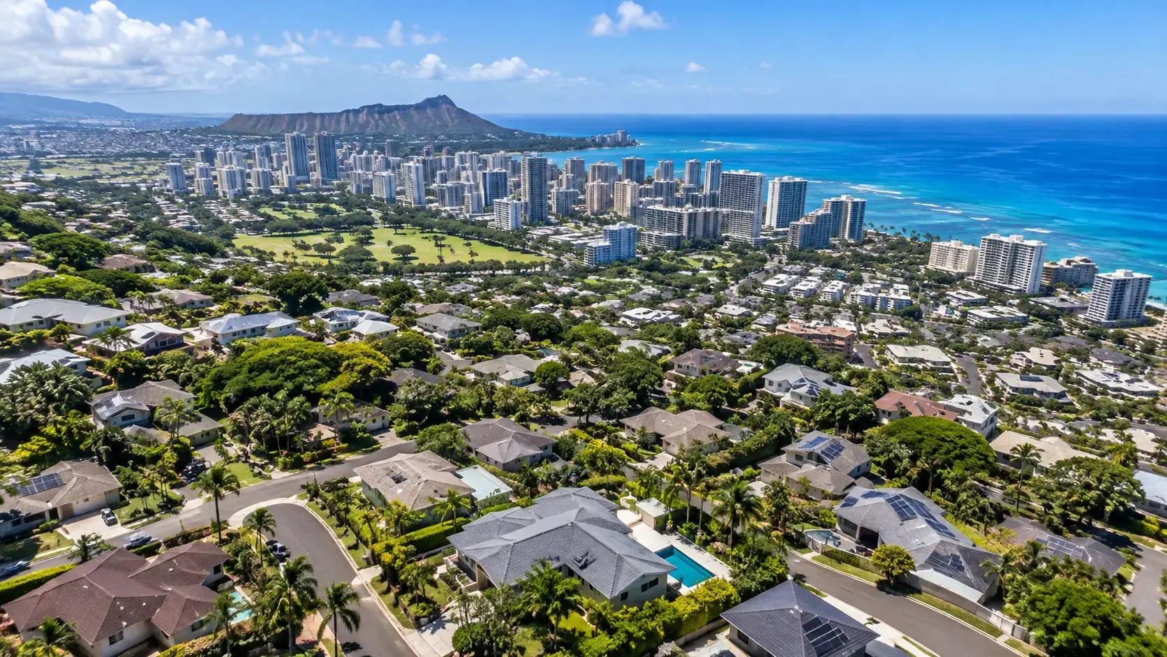 Aerial drone view of residential neighborhoods in Honolulu, Oahu, with Diamond Head and the Pacific Ocean in the background