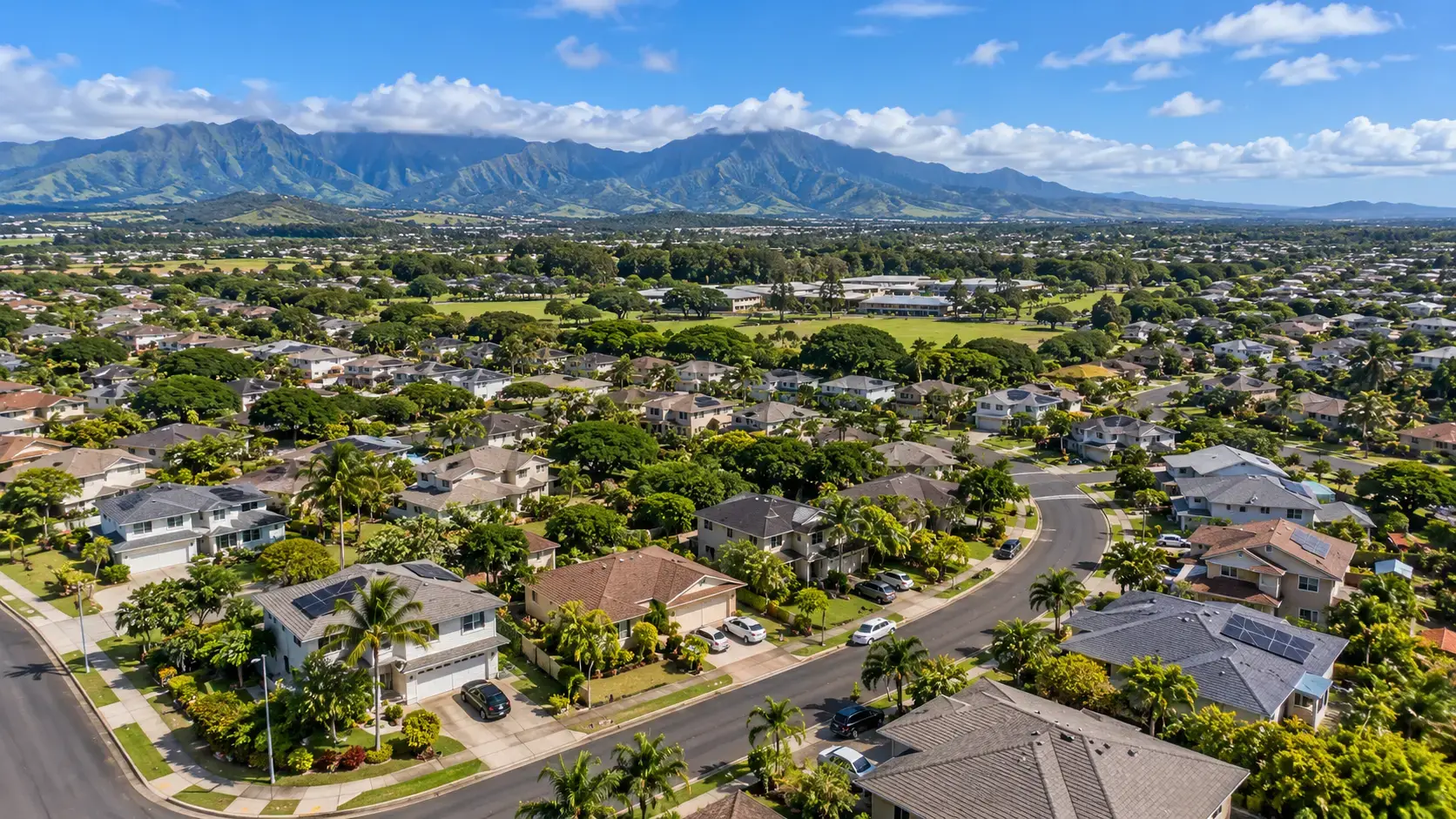 Aerial drone view of residential neighborhoods in Mililani, Oahu, Hawaii, with lush mountains in the background