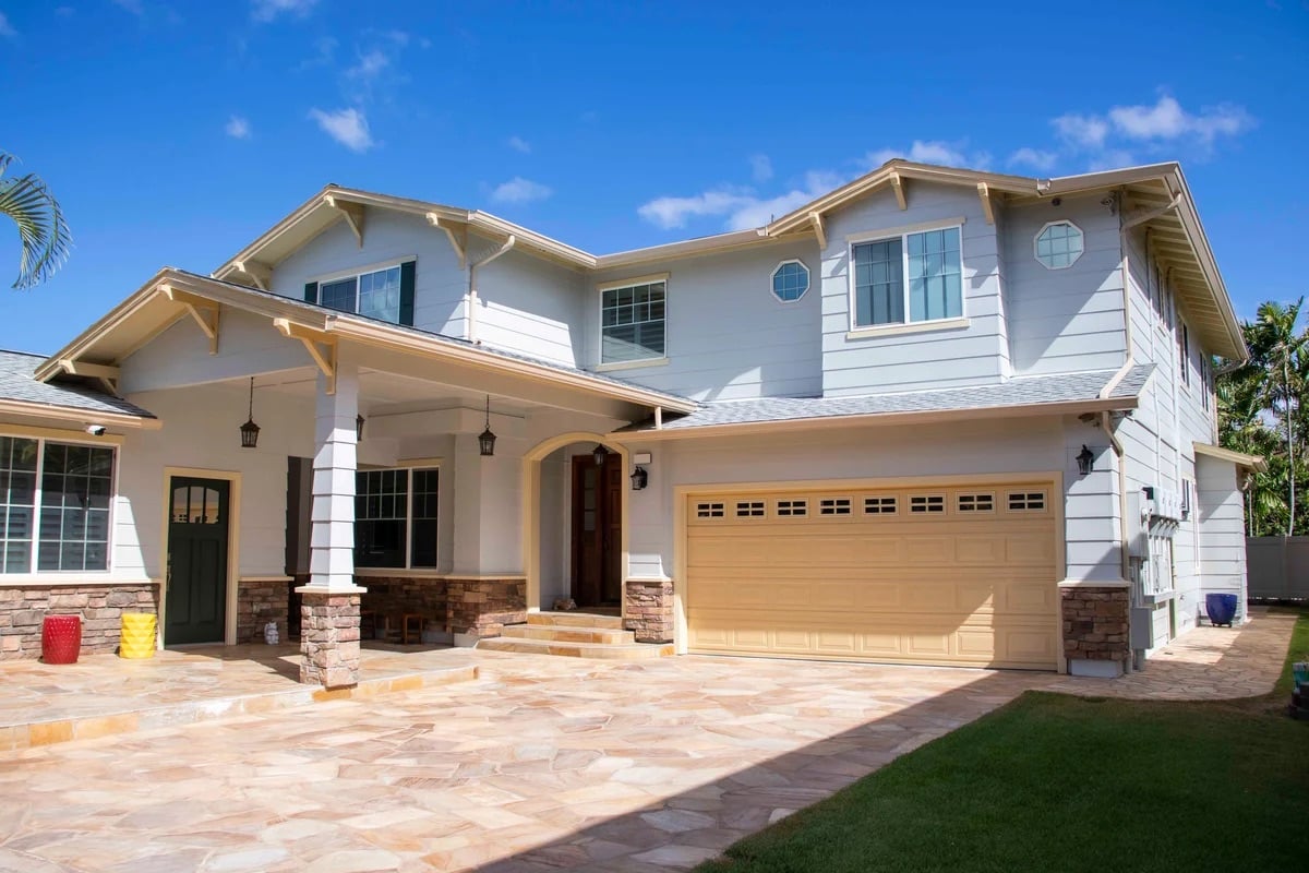 Newly painted two-story home exterior with columns and stone driveway in Honolulu, Oahu