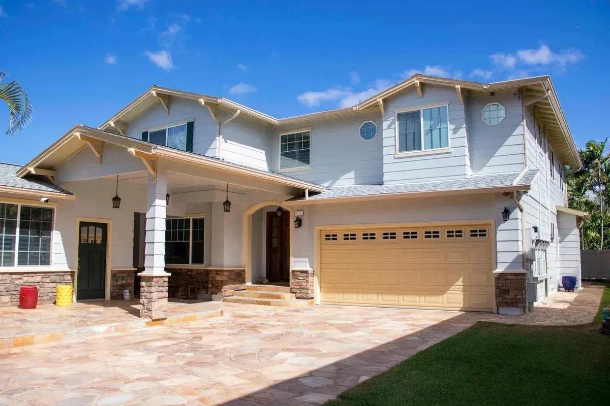 Newly painted two-story home exterior with columns and stone driveway in Honolulu, Oahu